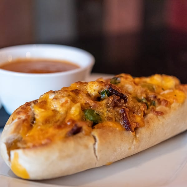 Cheesy bread with bacon and green onions, served with a side of dipping sauce.